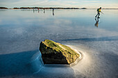 Stone peaking through the ice and ice-skaters