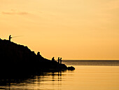 Silhouette of fishermen on shore at sunset