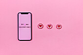 Smartphone und herzförmige Bonbons auf rosa Hintergrund