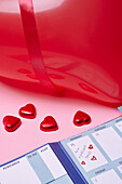 Heart-shaped candies and calendar on pink background