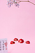 Herzförmige Bonbons und Kalender auf rosa Hintergrund