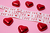 Heart-shaped candies and love message on pink background