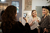 Woman photographing friends in cafe