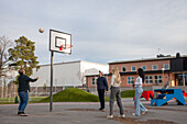 Teenage friends playing basketball outdoors