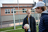 Lächelnde Freunde stehen auf dem Fußballplatz der Schule