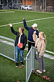 Friends standing on school soccer field and waving