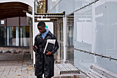 Junger Mann steht vor einem modernen Gebäude