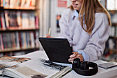 Studentin benutzt digitales Tablet in der Bibliothek