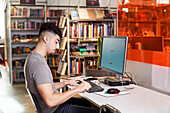 Male student using computer in library