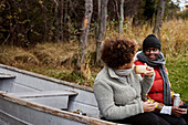 Freunde sitzen in einem alten Boot und trinken heiße Getränke