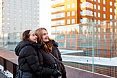 Smiling female couple looking at modern apartment buildings