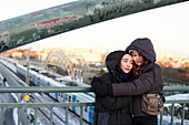 Young female couple standing on viaduct and hugging