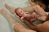 Father taking bath with newborn baby