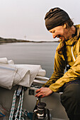 Smiling woman using camping stove on boat