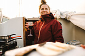 Lächelnde Frau mit einem Glas Wein auf einem Boot