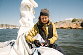 Woman folding sails on boat