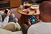 Family relaxing in living room and using phone and tablet