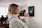 Frau nutzt Smart-Home-Anwendung auf einem an der Wand montierten Tablet