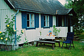 Girl sitting at table in front of wooden house