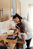 Mother and daughter in kitchen using tablet while baking