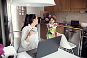 Woman using laptop in kitchen