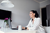 Woman in kitchen using laptop