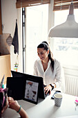 Woman in kitchen using laptop