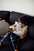 Mädchen benutzt digitales Tablet auf dem Sofa