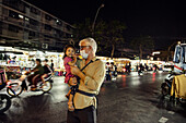 Grandfather holding granddaughter in street at night
