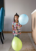 Portrait of girl holding balloons at home
