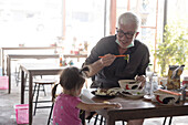 Grandfather and granddaughter eating lunch in restaurant