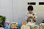 Junge Frau über dem Essen sitzend und telefonierend