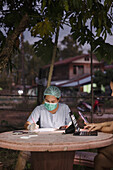 Nurse in protective clothing filling paperwork