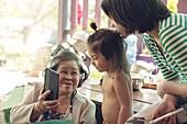 Großmutter und Enkelkinder beim Telefonieren mit dem Smartphone