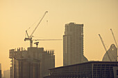 Cityscape with skyscrapers and construction cranes at sunrise