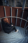 Junge Frau sitzt auf einer Treppe
