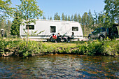 Family relaxing in front of camper trailer