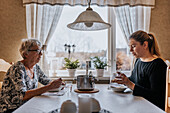 Grandmother and adult granddaughter eating at home
