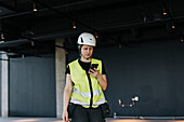 Arbeiter auf der Baustelle benutzt ein Mobiltelefon
