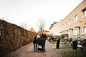 Mothers with baby stroller walking in residential area