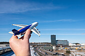 Man holding toy airplane against blue sky