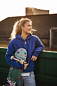 Lächelndes jugendliches Mädchen hält Skateboard