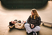 Teenage girls with skateboards relaxing in skatepark