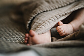 Nackte Füße eines neugeborenen Babys in eine Decke gewickelt