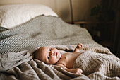 Porträt eines neugeborenen Babys, das im Bett liegt