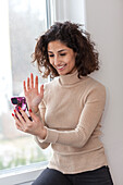 Lächelnde junge Frau winkt während eines Videogesprächs mit einem Smartphone