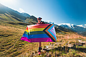 Mann hält LGBTIQ Community Flagge in den Bergen