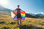 Mann hält LGBTIQ Community Flagge in den Bergen