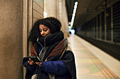 Woman using phone at train station