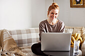 Lächelnde Frau benutzt Laptop zu Hause